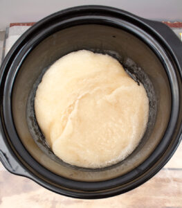 soap batter in a slow cooker with a thicker consistency and few bubbles around the edges and holding shape slightly after having been folded